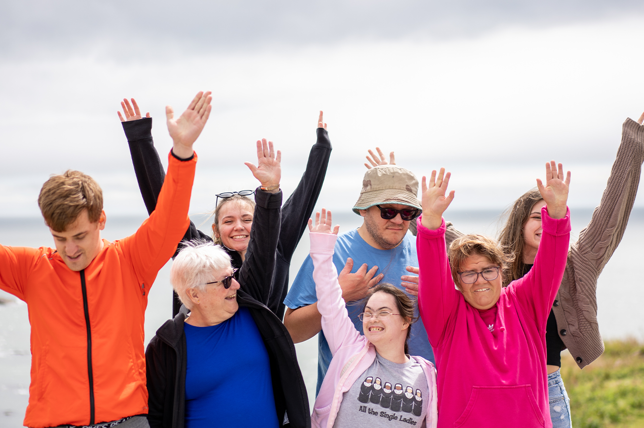 Fredericton - A group of community members arms in the air outside