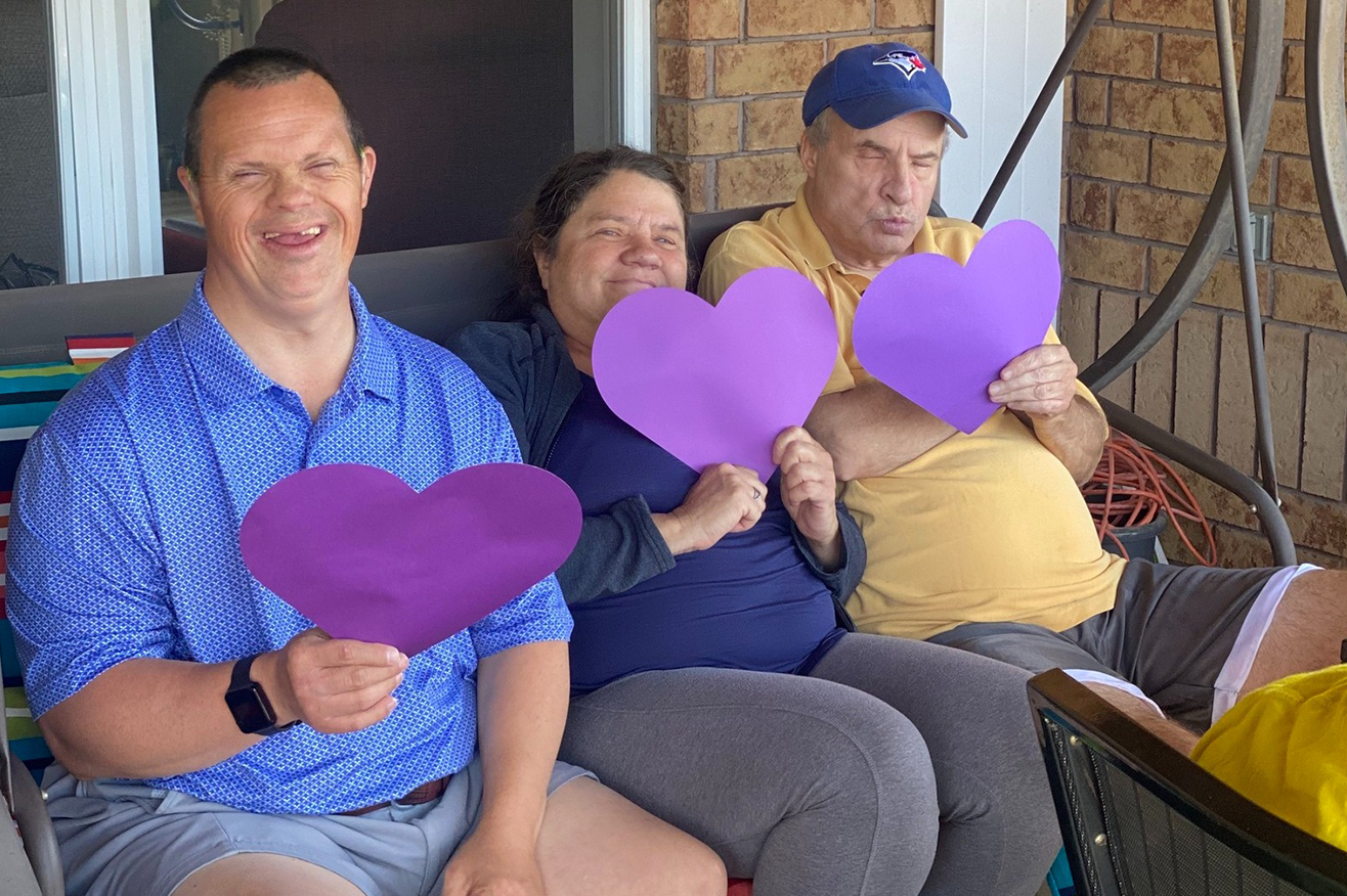 Sudbury - Three community members on a swing, holding a heart shaped piece of paper